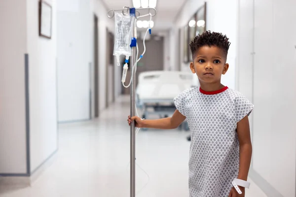 非洲裔美国男孩患者与滴注站在医院走廊与复制空间 医疗和保健服务 — 图库照片