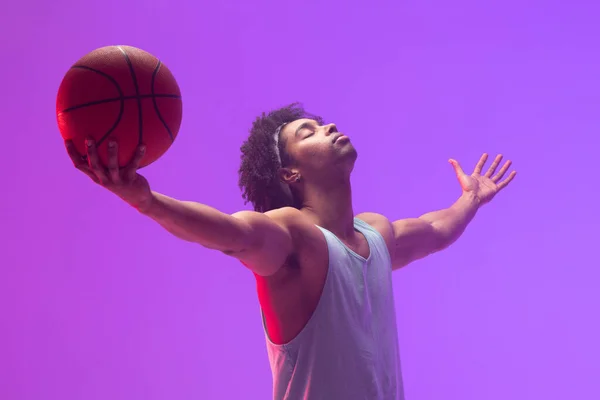 Image of biracial basketball player with basketball and arms stretched on neon purple background. Sports and competition concept.
