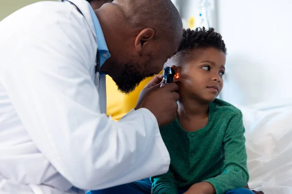 Африканский Врач Американец Использующий Отоскоп Обследования Уха Больного Мальчика Больнице — стоковое фото