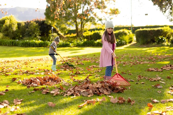 秋天花园里快乐的高加索女孩和男孩在刷叶的图像 秋天和户外时间的概念 — 图库照片
