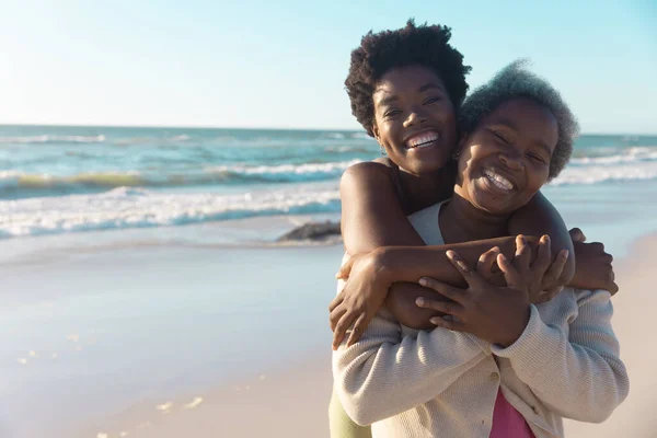 アフリカ系アメリカ人の若い娘たちは 海辺に立ちながらお母さんを抱きかかえている コピースペース 変更されていない 一緒に 楽しさと自然コンセプト — ストック写真