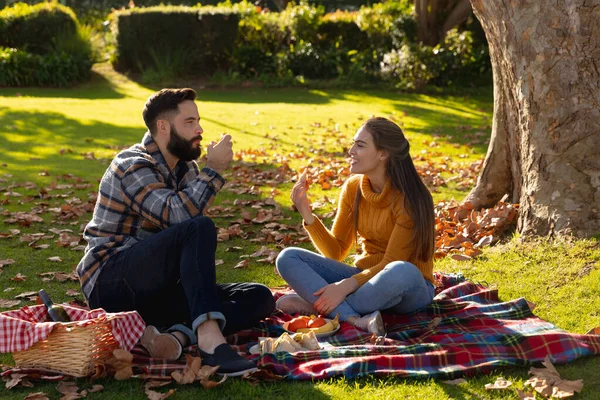 幸せな白人のカップルはピクニックをし 日当たりの良い秋の庭で話して敷物に座っています 国内生活 ロマンスと団結の概念 — ストック写真