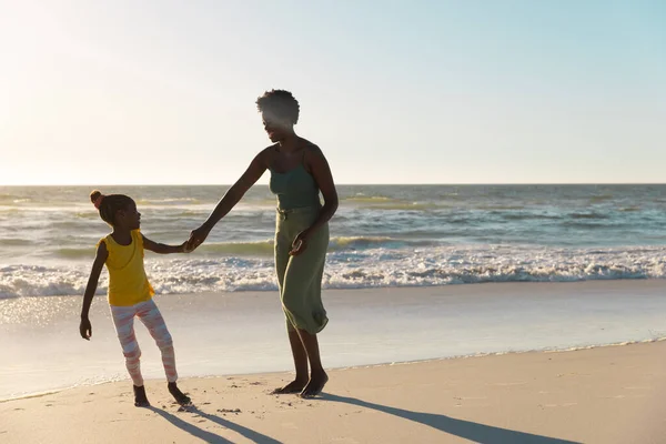 アフリカ系アメリカ人の母親と娘が手を取り合い 澄んだ空を背景に海岸で楽しむ コピースペース 変更されていない 一緒に 子供時代と自然コンセプト — ストック写真