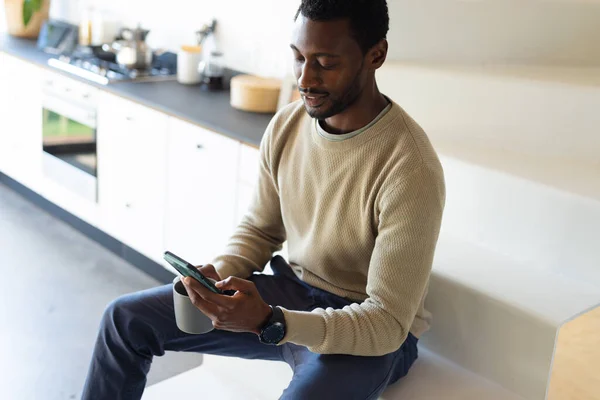 Szczęśliwy Amerykanin Afryki Siedzi Schodach Kuchni Pije Kawę Używa Smartfona — Zdjęcie stockowe