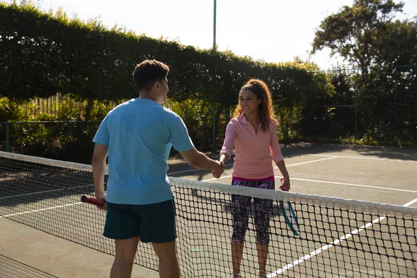 在阳光灿烂的室外网球场上 一对嬉笑的小鸟在打网球 他们在网球网上握手 包容性 健康爱好 健身和闲暇时间概念 — 图库照片