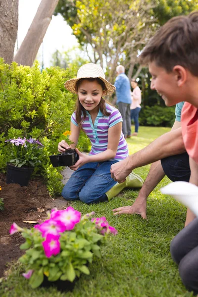 一个白人家庭一起在花园里种花的垂直图片 家庭外出时间 — 图库照片