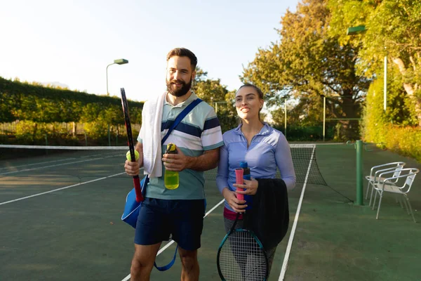 在打完网球后 笑笑的哥卡夫妇拿着球拍在室外网球场上散步 健康爱好 健身和闲暇时间概念 — 图库照片