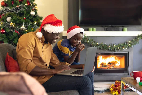 非洲裔美国人的父亲和儿子坐在沙发上 使用笔记本电脑 圣诞节 家庭时间和采用技术概念的庆祝活动 — 图库照片