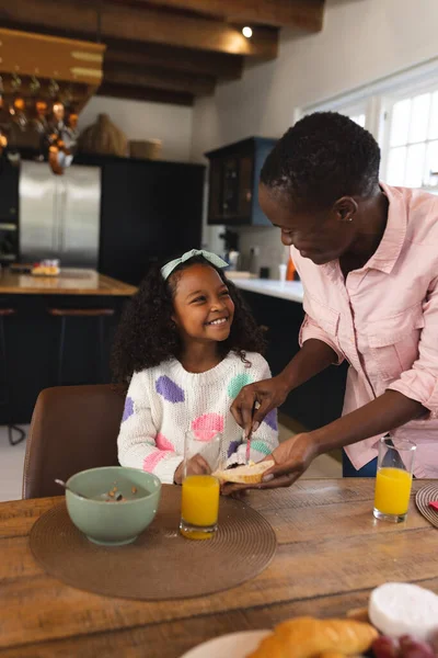 母と朝食を食べる幸せなアフリカ系アメリカ人の少女の垂直画像 家族と一緒に質の高い時間を過ごすコンセプト — ストック写真
