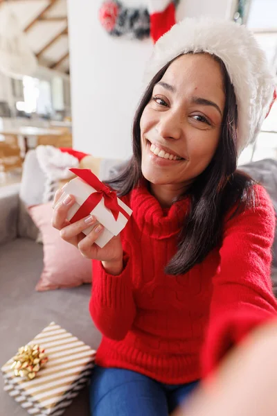 幸せな出産の女性サンタの帽子をかぶって リビングルームのソファに座って ビデオ通話をしています クリスマスだけで家で質の高い時間を過ごす — ストック写真