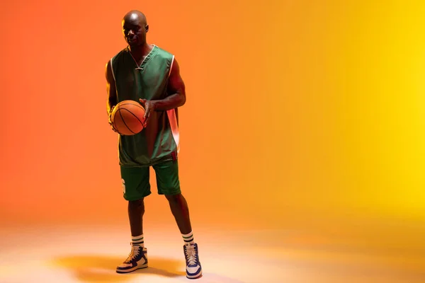 バスケットボールとネオンオレンジの背景にスペースをコピーしたアフリカ系アメリカ人バスケットボール選手のイメージ スポーツ 競技の概念 — ストック写真