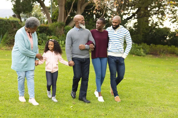 Image of happy multi generation african american family walking together outdoors. Extended family, spending quality time together concept.