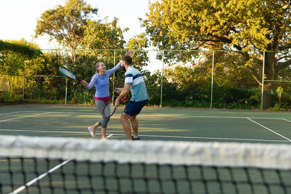 快乐的高加索夫妇在室外网球场打网球拥抱 健康爱好 健身和闲暇时间概念 — 图库照片