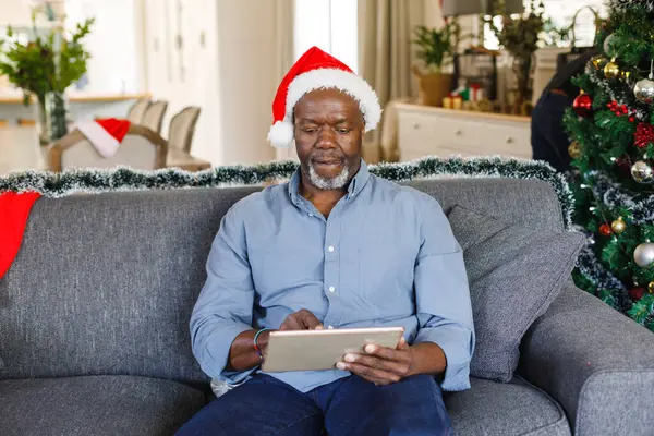 Mutlu Kıdemli Afro Amerikan Adam Noel Baba Şapkalı Tablet Kullanıyor — Stok fotoğraf