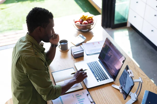 快乐的非洲裔美国男人站在厨房的桌旁 用笔记本电脑和平板电脑 独自在家度过高质量的时光 — 图库照片