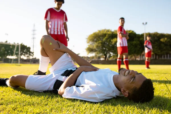 多种族男性运动员看着受伤的对手躺在运动场的草地上 复制空间 团队运动和竞赛概念 — 图库照片