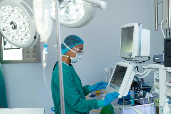 Çift Irklı Kadın Cerrahın Ameliyathanede Bilgisayar Destekli Tıbbi Ekipman Kullanışının — Stok fotoğraf