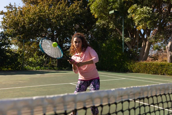 Biracial Kvinne Spiller Tennis Returnerer Ball Nettet Solrik Utendørs Tennisbane – stockfoto