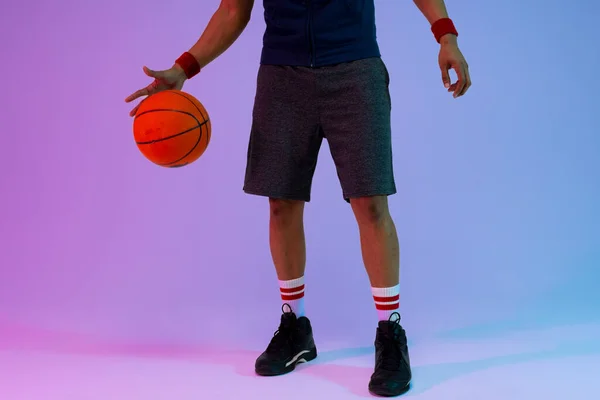紫から青の背景にバスケットボールを持つ出生バスケットボール選手の低セクションのイメージ スポーツ 競技の概念 — ストック写真