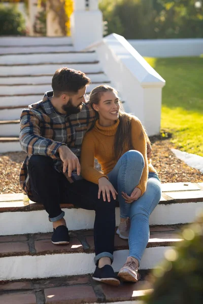 テラスの階段に座っている幸せな白人のカップルは笑顔で 日当たりの良い秋の庭で抱擁します 国内生活 ロマンスと団結の概念 — ストック写真