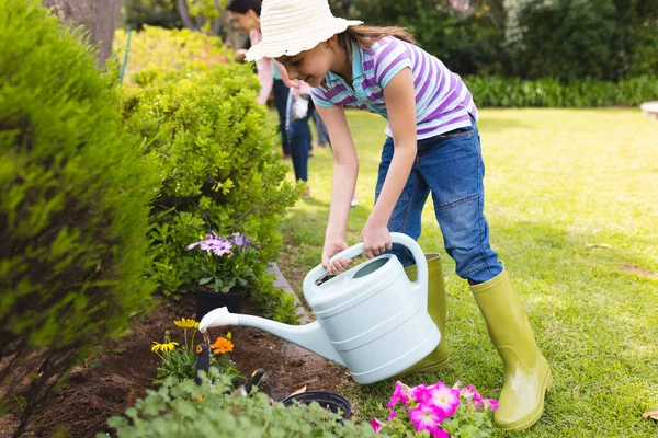 Caucasian mother and daughter spending time together in the garden and watering plants. Family time spending outside , garden, gardening, concept.