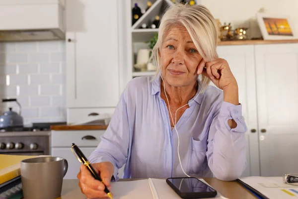 Son Sınıf Beyaz Kadın Kulaklık Takıyor Mutfaktaki Masada Oturuyor Video — Stok fotoğraf