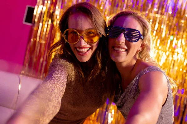 两个戴着太阳镜 面带微笑的高加索女性朋友在夜总会拥抱的画像 出去玩 友谊和派对的概念 — 图库照片