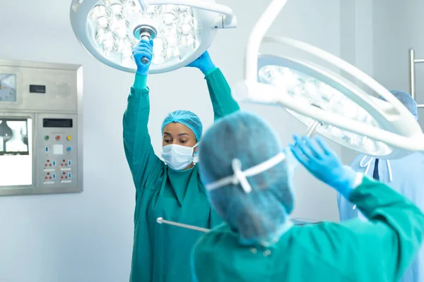 Biracial Female Surgeon Colleague Adjusting Lights Operating Theatre Operation Hospital — Stock Photo, Image
