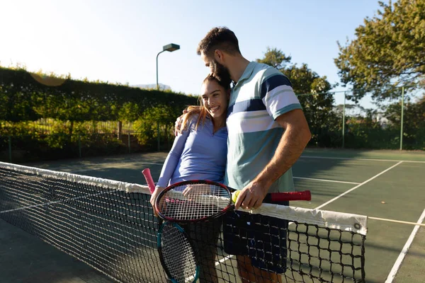快乐的高加索夫妇在室外网球场打网球 拥抱在网下 健康爱好 健身和闲暇时间概念 — 图库照片