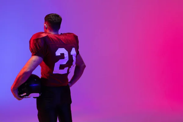 ネオンピンクと青の照明でヘルメットを保持白人男性アメリカのサッカー選手 スポーツ トレーニング アクティブなライフスタイルの概念 — ストック写真