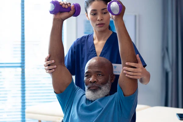 Různorodý Ženský Fyzioterapeut Pomáhá Staršímu Pacientovi Cvičit Činkami Nemocniční Lékařské — Stock fotografie