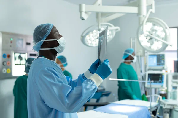Afrika Kökenli Amerikalı Erkek Cerrah Ameliyathanede Röntgen Çekiyor Meslektaşları Arkada — Stok fotoğraf