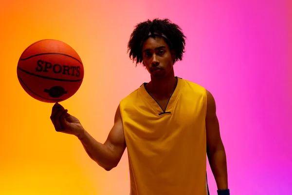 ピンクからオレンジ色の背景にバスケットボールを回転させる出生バスケットボール選手のイメージ スポーツ 競技の概念 — ストック写真