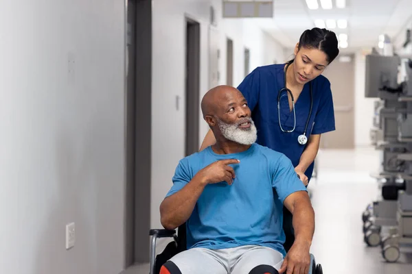 Diverse Female Doctor Pushing Senior Male Patient Wheelchair Corridor Copy — Stock Photo, Image