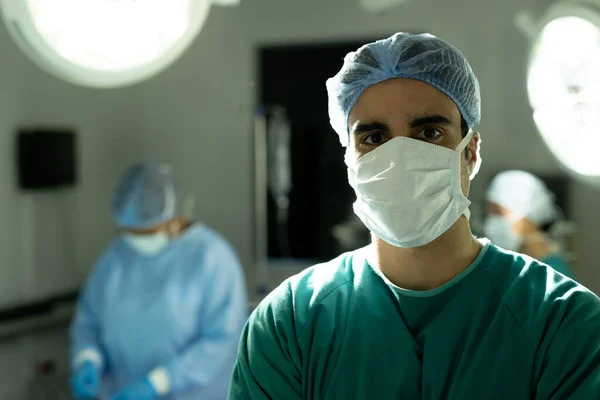 Ameliyathanede Meslektaşlarıyla Birlikte Cerrahi Şapkalı Maskeli Çift Irklı Erkek Cerrahın — Stok fotoğraf