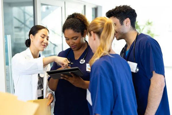 Four Happy Diverse Healthcare Colleagues Looking Tablet Together Hospital Corridor — Stock Photo, Image