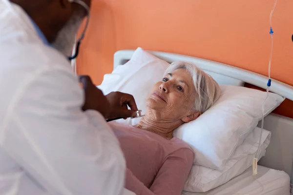 ベッドの上で高齢女性患者を検討聴診器を使用して多様な高齢男性医師 コピースペース 医療サービス — ストック写真