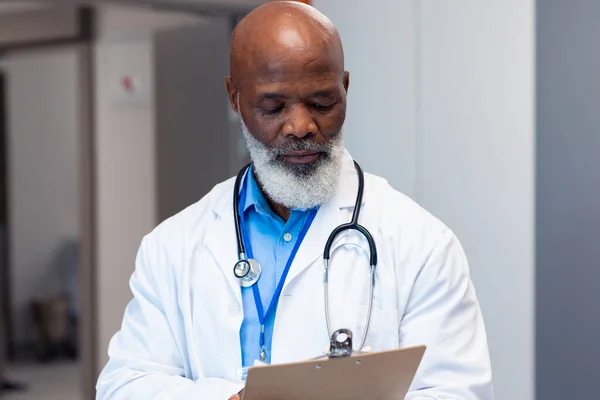 アフリカ系アメリカ人のシニア男性医師は 病院の廊下 コピースペースでメモを読む 医療サービス — ストック写真
