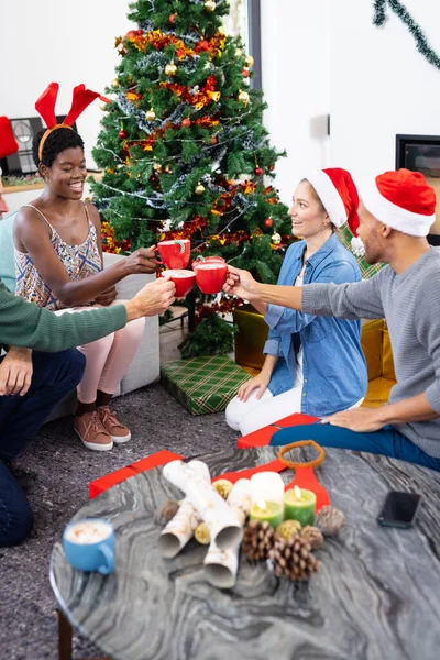 ホットチョコレートマグカップでトーストを作るクリスマスを祝う幸せな多様な友人の垂直イメージ クリスマス お祝い 包括性とライフスタイルの概念 — ストック写真