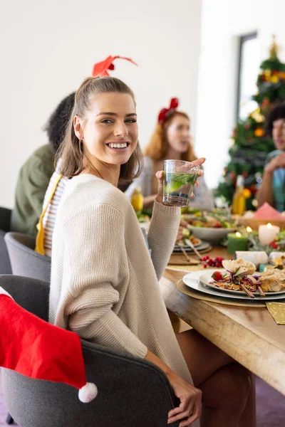 快乐多样的朋友坐在桌旁 在圣诞节共进晚餐的画像 圣诞节 包容和生活方式概念 — 图库照片