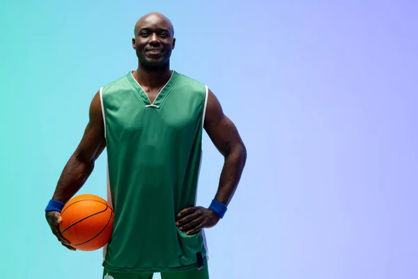 緑色から青色の背景にバスケットボールでアフリカ系アメリカ人のバスケットボール選手を笑顔のイメージ スポーツ 競技の概念 — ストック写真