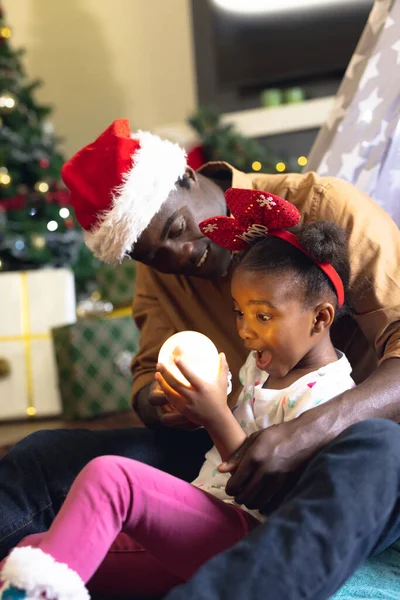 アフリカ系アメリカ人の父親と娘の垂直写真がおしっこに座っています クリスマス 家族の時間とお祝いの概念 — ストック写真