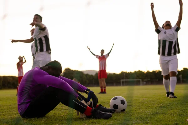 多种族悲伤的守门员坐在草地上 手挽手举枪庆祝胜利 复制空间 比赛和运动 — 图库照片