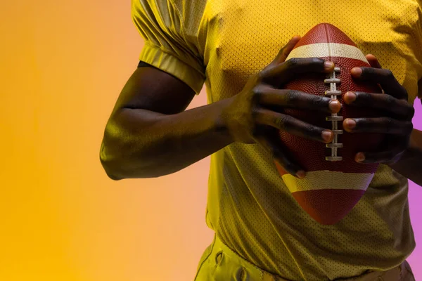 Środkowa Część Afrykańskiego Amerykańskiego Męskiego Futbolisty Neonowym Fioletowym Żółtym Oświetleniem — Zdjęcie stockowe
