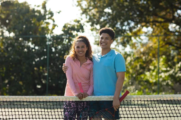 Portrait Smiling Biracial Couple Playing Tennis Embracing Sunny Outdoor Tennis — Stock Photo, Image