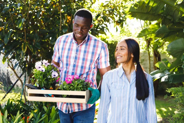 Feliz Casal Diverso Carregando Flores Para Plantar Andando Jardim Sorrindo — Fotografia de Stock