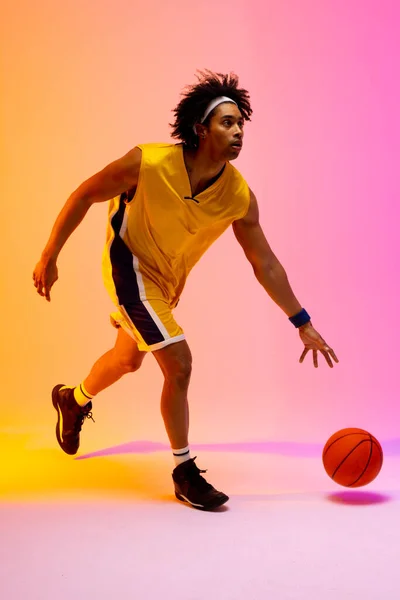 Afbeelding Van Biracial Basketbalspeler Stuiteren Basketbal Roze Tot Oranje Achtergrond — Stockfoto
