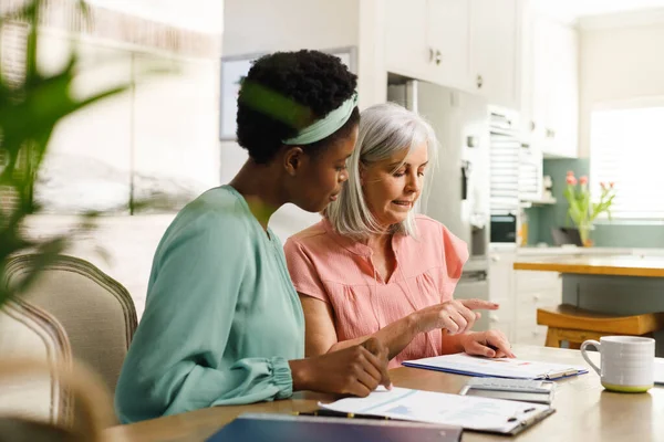 与非洲裔美国女金融顾问交谈的是一位资深的高加索妇女 退休和包容性概念 — 图库照片