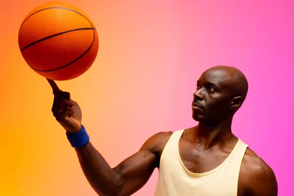 オレンジとピンクの背景でバスケットボールをしているアフリカ系アメリカ人のバスケットボール選手のイメージ スポーツ 競技の概念 — ストック写真