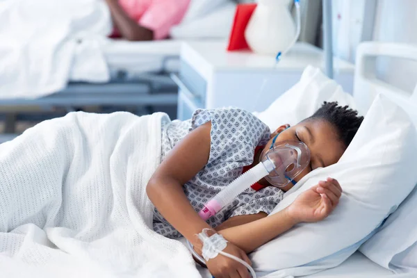 人工呼吸器を装着したアフリカ系アメリカ人の少年がコピースペース付きの病院のベッドで眠っていた 医療サービス — ストック写真
